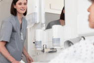 Environmental services staff cleaning sink while talking to patient