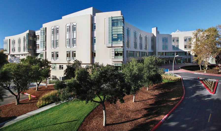 Exterior image of modern hospital with a road and landscaped grounds