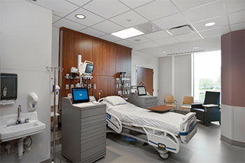 A patient's hospital room with a bed, wood paneling, and medical equipment