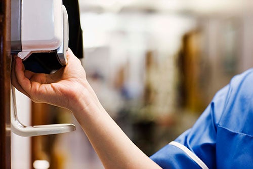 nurse using a hand sanitizing station