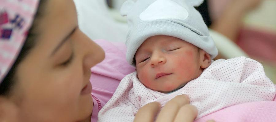 A mother holds a newborn baby in a hospital bed