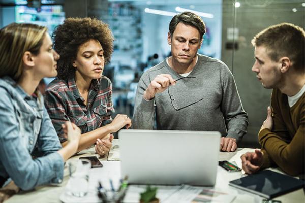 Four coworkers huddled around a table in meeting room