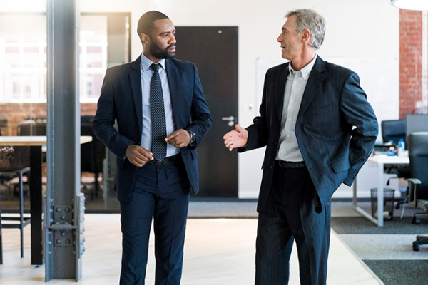 Two well-dressed professionals walking and talking in commercial facility