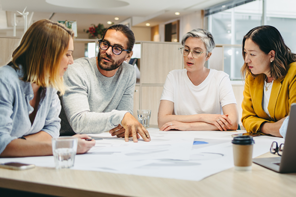 Group of architects sitting around table reviewing plans