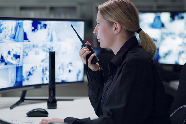 Security officer watching footage and speaking into radio