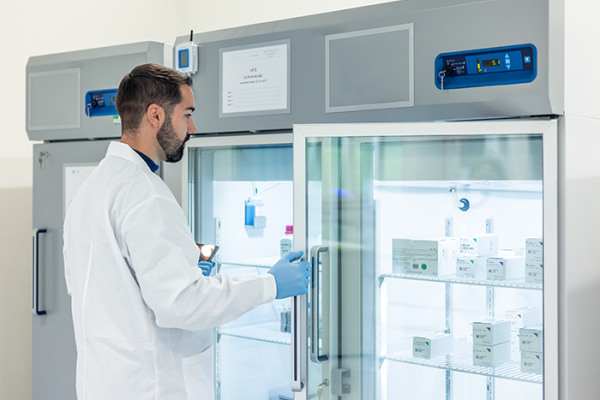 Pharmacist opening fridge with medications inside 