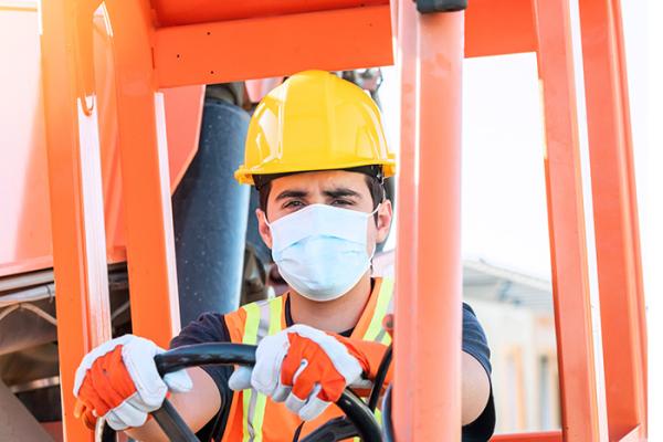 Construction worker wearing mask operating equipment