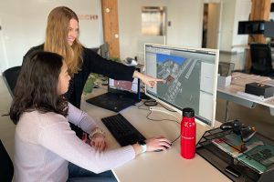 Two colleagues analyzing digital twin on desktop computer screen