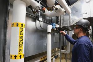 APM steam technician working on pipes