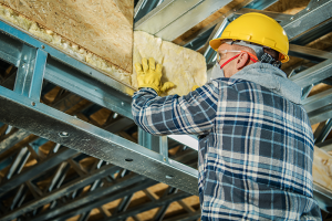 Construction worker wearing mask installing insulation 