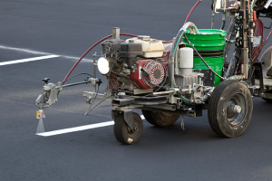 Machine painting parking spot lines on pavement