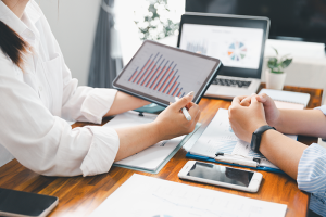 Woman presenting data on tablet to person sitting on other side of the desk 