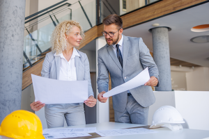 Woman and man architect holding plans and reviewing them 