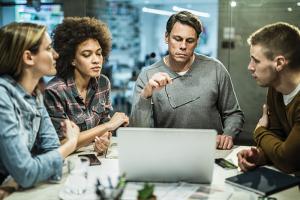 Four coworkers huddled around a table in meeting room