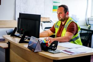 Facility manager wearing high-vis vest sitting at desk