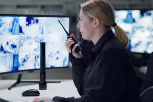 Security officer watching footage and speaking into radio